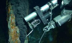 Rameno manipulátoru dálkově ovládaného robota „Jason“ odebírá vzorek tekutiny proudící z hydrotermálního otvoru v hornině. Obsahuje plyny, které jsou kvůli vysokému tlaku na dně oceánu v kapalné formě. Metan i vodík nejsou dílem mikroorganismů v sedimentu. Původ je abiotický a svůj podíl na nich mají  olivíny. Kredit: Chris German / WHOI / NSF, NASA / ROV Jason 2012, Oceanografická instituce Woods Hole.