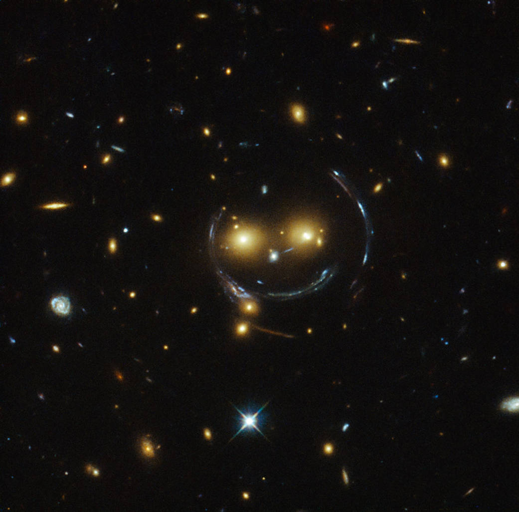 Pozorování gravitační čočky pomocí Hubblova dalekohledu, v centru obrázku je galaktická kupa SDSS J1038+4849 (zdroj NASA).