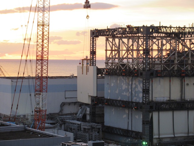 Jeřáb přemisťuje poslední panel provizorního krytu prvního bloku (zdroj TEPCO).