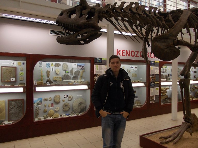 Autor u repliky kostry druhu Carnotaurus sastrei, vystavené od roku 2008 v expozici Chlupáčova muzea historie Země při Ústavu geologie a paleontologie PřF UK. Kostra osm metrů dlouhého teropoda je zblízka impozantní, i když se samozřejmě nemůže rovna