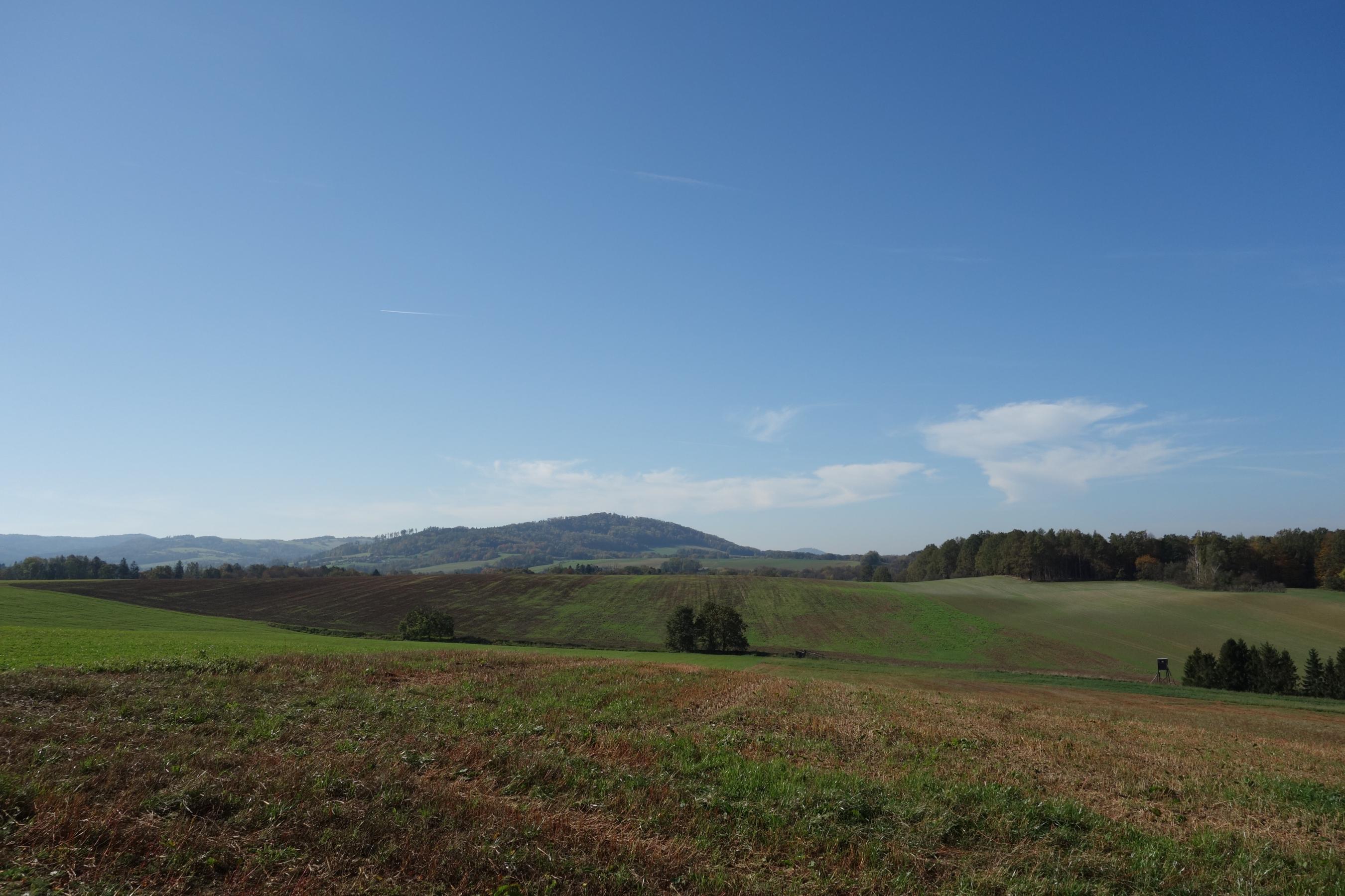 Pohled z vrchu Janský sloup (316 m n. m) ve směru na jihozápad. Jeden bludný balvan na Hoheneggerově mapě se nacházel napravo ve vzdálenosti cca 850 m, druhý cca 850 m nalevo. V pozadí Libhošťská hůrka (494 m n. m.) – 1,5 km dlouhý hřeben pokrytý les