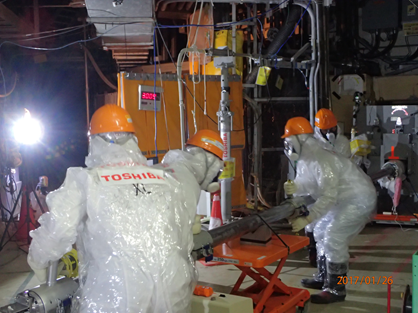 Skupina pracující na zasunutí trubky do potrubí přímo u vybudovaného přístupu k potrubí (zdroj TEPCO).
