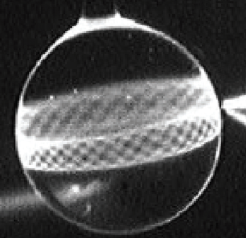 Optické módy šeptající galerie ve skleněné kouli o průměru 300 ?m experimentálně zobrazené fluorescenční technikou. Hrot optického vlákna (vpravo) excituje mody v červené oblasti optického spektra. Kredit: NASA's jet propulsion laboratory, volné dílo