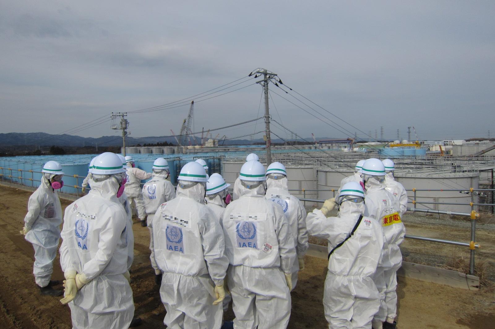 PracovnĂ­ci MezinĂˇrodnĂ­ atomovĂ© agentury pĹ™ed nĂˇdrĹľemi na kontaminovanou vodu (zdroj TEPCO)