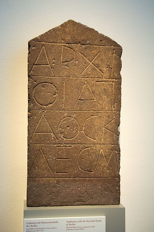 Stéla s inskripcí: Archió, (její otec) Agathoklés... Mélos. Vápenec, kolem roku 500 před n. l. Berlin, Altes Museum, Sk 1161. Tvar písmen gamma a sigma je specifický pro archaické inskripce na Mélu (Milosu). Kredit: Zde, Wikimedia Commons. Licence CC