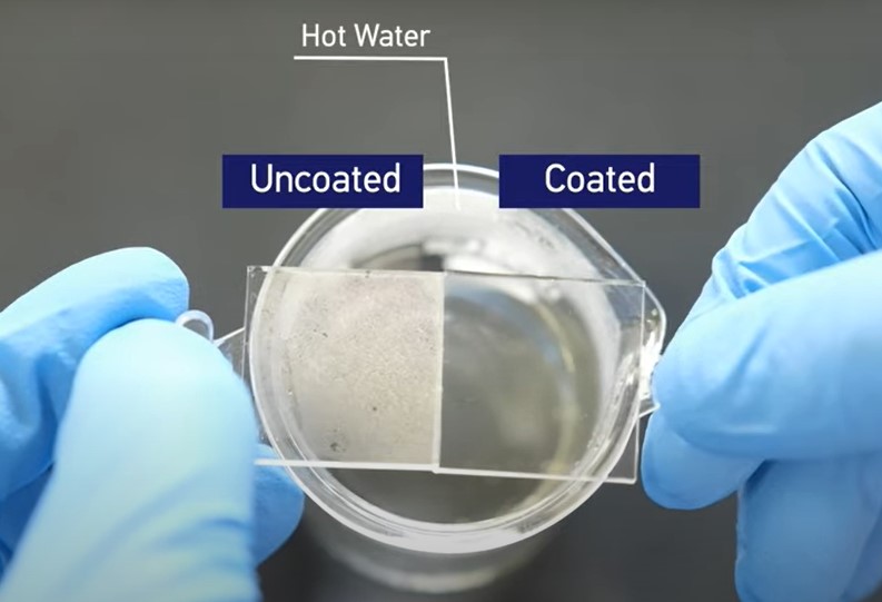 Dva stejné čtvercové tabulky z polykarbonátu nad horkou vodou, levý bez úpravy, pravý po nanesení SiO2/TiO2 povlaku. Kredit: NTU Singapore.