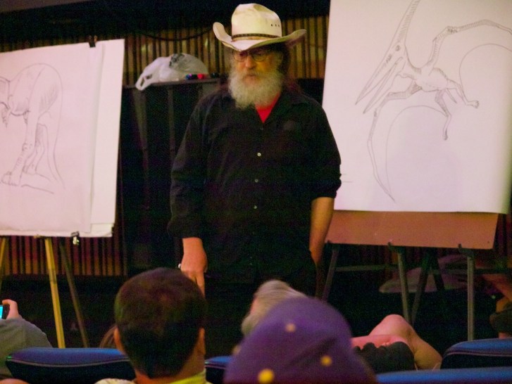 Autor knihy Robert T. Bakker při jedné ze svých přednášek v roce 2011. Bakker dlouhodobě využívá své výborné ilustrátorské schopnosti, aby podpořil své často poněkud neobvyklé názory. Mezi ty patří například i představa živorodých sauropodů. Kredit: 