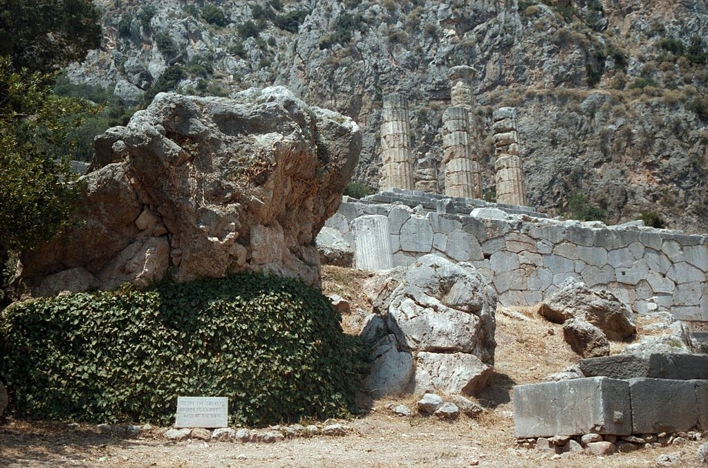 Vlevo je Sibyllina skála (dole porostlá břečťanem), vedle ní skála Gaie, víc vpravo zbytek skály bohyně Létó. Nad nimi polygonální zdivo (548-513 před n. l.) opěrné terasy Apollónova chrámu, stav r. 1998. Kredit: Zde, Wikimedia Commons. Licence CC 4.