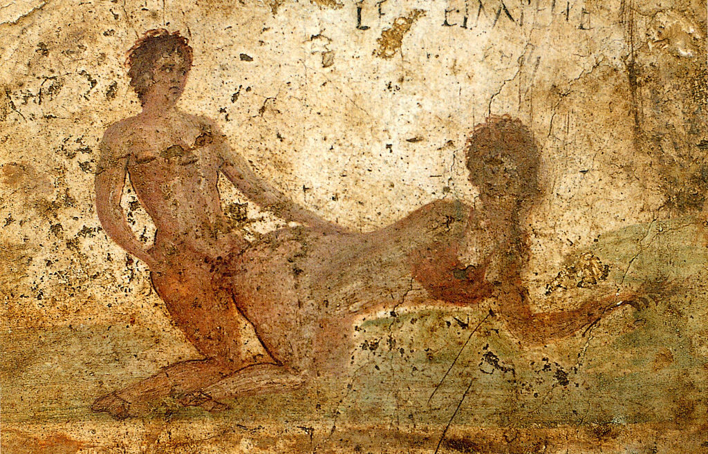 Římská freska z Pompejí (Casa del Re di Prussia), scéna z nevěstince hrubšího zrna, 69-79 n. l. Muž se tváří, že sleduje spíše latinský nápis na zdi: LENTE IMPELLE. „Strč pomalu“. Archeologické muzeum v Neapoli, Inv. č. 27690. Kredit: WolfgangRieger,