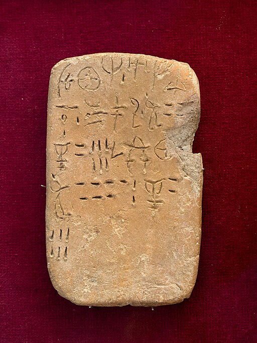 Tabulka s nápisem v lineárním písmu A, z paláce v Petras. Archeologické muzeum v Sitii, S.M. 9099. Může zaznamenávat počet zaměstnanců a množství obilovin (příděly, naturálie). Kredit: Zde, Wikimedia Commons. Licence CC 4.0.