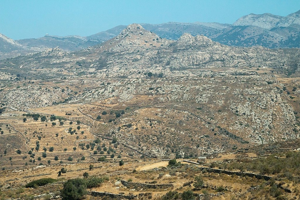 Východní část oblasti Cheimarros na Naxu od jihu, z okolí hlavní silnice do Chalki. Dominantou je hrad Apano Kastro nad obcí Tsikalario. Naxos. Kredit: Zde, Wikimedia Commons. Licence CC 4.0.