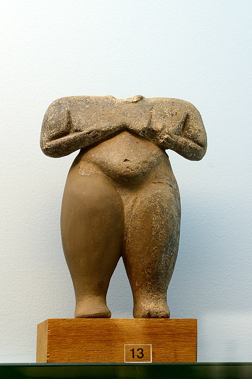 orzo keramické figurky ženy (ve stylu steatopygous), držící se za ňadra. Neolit, 5000 až 4400 před n. l. Kanellopoulovo muzeum, ? 1865. Kredit: Zde, Wikimedia Commons. Licence CC 4.0.