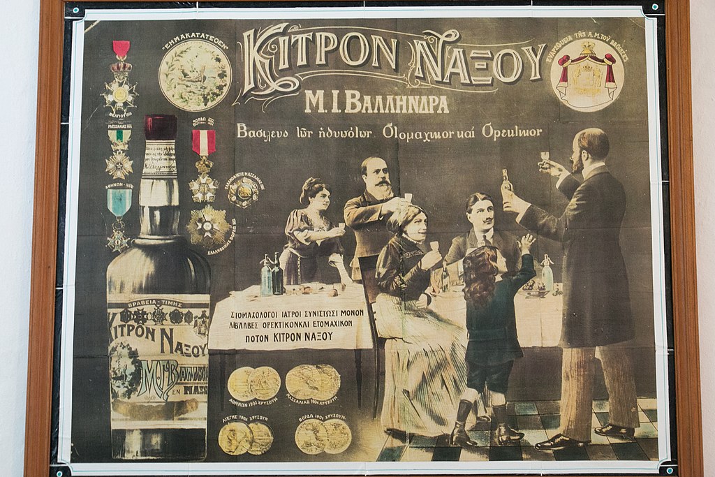 Osvěta přináší Kitron Naxou do každé lepší rodiny, dítko ovšem vzpíná ručičky marně. Řecký nápis: „Ústní lékaři (možná spíše zubaři) doporučují pouze neškodný aperitiv a ústní nápoj Kitron Naxou.“ Kredit: Zde, Wikimedia Commons. Licence CC 4.0.