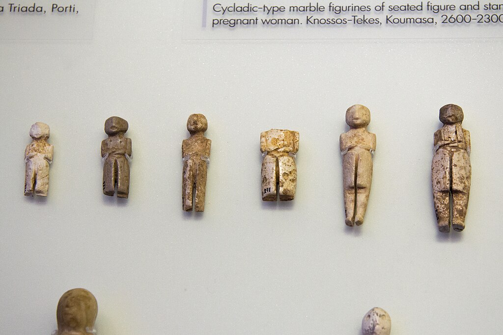 Minojské figurky, asi inspirované kykladskými „idoly“. Většinou z Knóssu, většinou řezané z kosti, někdy z mramoru, později i ze slonoviny. Raná doba bronzová, 2600 až 2300 před n. l. Archeologické muzeum v Irakliu. Kredit: Zde, Wikimedia Commons. Li