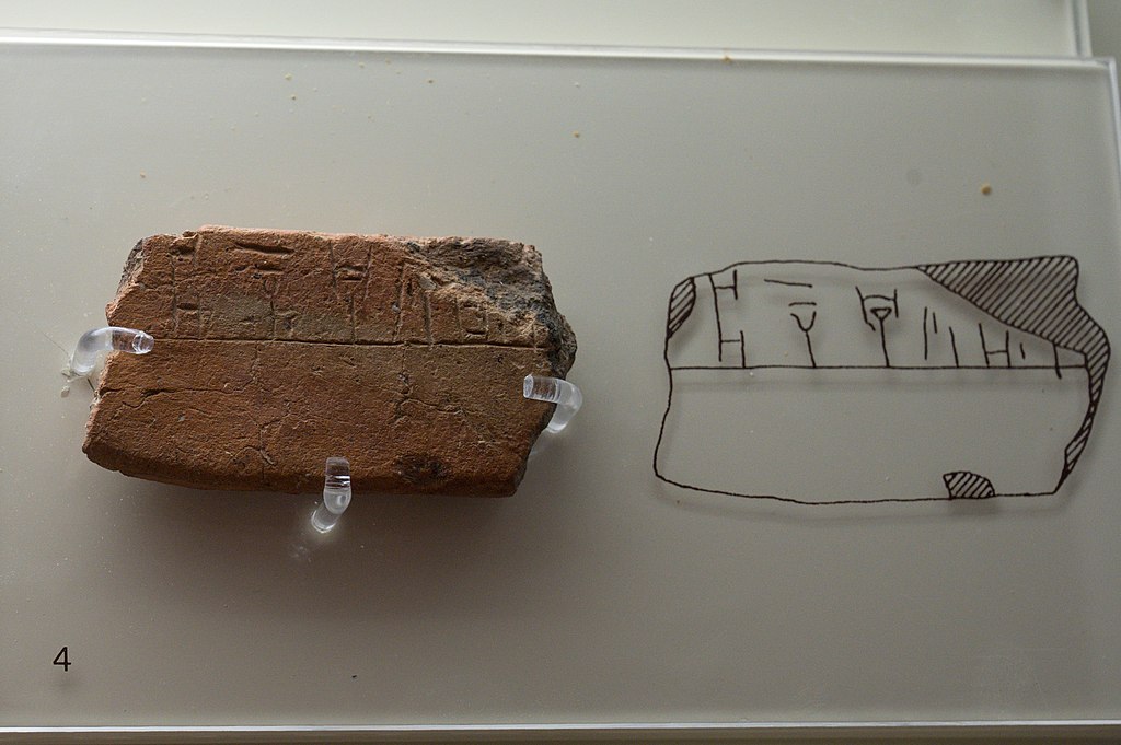 Tabulka s nápisem v lineárním písmu B z kultovního centra v Mykénách: „Athéna přijímá.“ 1400-1180 před n. l. Archeologické muzeum v Mykénách, MM 2045. Kredit: Zde, Wikimedia Commons. Licence CC 4.0.