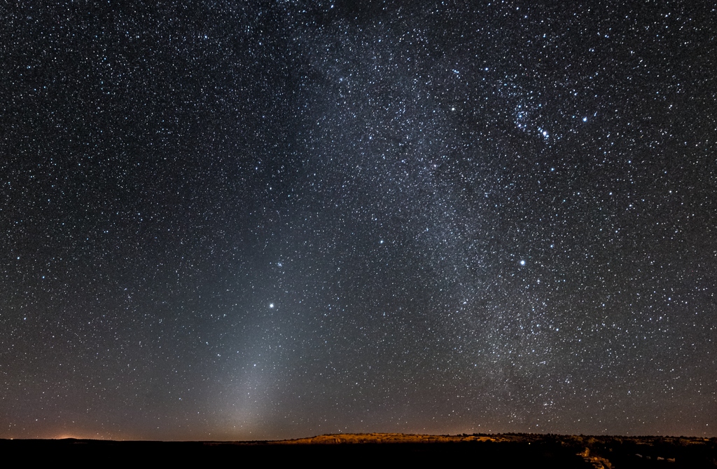 Zodiakální svit a Mléčná dráha. Canyon de Chelly, Arizona. (Zleva dole se zářící skvrna táhne kousek vpravo nahoru směrem k Jupiteru.) Kredit: Zolt Levay Photography, Wikimedia Commons. Public domain.