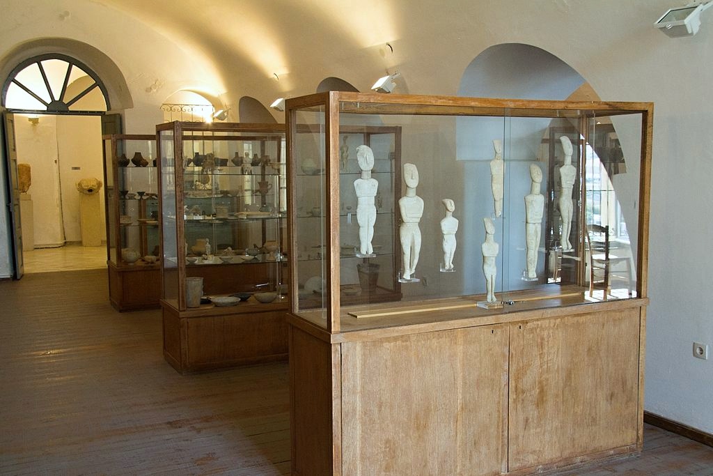 Pohled zevnitř ke vchodu do sálu starokykladské sbírky (galerie IV) Archeologického muzea na Naxu. V popředí je vitrína 3, za ní 2 a 1. Kredit: Zde, Wikimedia Commons. Licence CC 3.0.