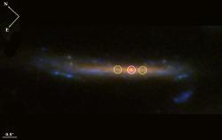 Rudý veleobr Quyllur byl nalezen díky gravitačnímu čočkování velmi hmotnou kupou galaxií El Gordo (zdroj NASA).