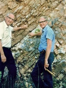 Luis Alvarez (vlevo) a jeho syn Walter u dobře patrné jílové vrstvy uložené na přelomu křídy a paleogénu před 66 miliony let. Jedná se o lokalitu v rokli Gola del Bottaccione u italského městečka Gubbio, kde došlo k zásadnímu objevu při výzkumu velkého vymírání na konci křídy. Snímek je pravděpodobně z roku 1981. Kredit: U. S. Government – Lawrence Berkeley Laboratory; Wikipedia (volné dílo).