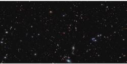Na obrázku pořízeného kamerou NIRCam (zaměřena na blízkou infračervenou oblast spektra) je okolo 20 000 galaxií. Jde o oblast mezi souhvězdími Ryb a Andromedy. Pozorovaný kvasar J0199+2802 je ve středu snímku (zdroj NASA).