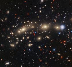 Kupa galaxií MACS0416 na kombinovaném snímku z výsledku spojení infračerveného snímku Webbova teleskopu a viditelného snímku z Hubblova dalekohledu. Umělé barvy umožňují zobrazit celé spektrum od infračervené až po viditelnou oblast. Dlouhé vlnové délky jsou červené a krátké vlnové délky jsou modré. Extrémně červené objekty jsou ty s extrémním rudým posuvem (zdroj NASA).