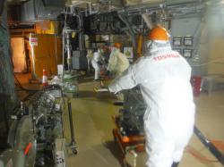 Pracovníci firmy Toshiba zavádí robota do potrubí (zdroj TEPCO).