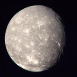Největší měsíc Uranu – Titanie.  Barevná kompozice byla vytvořena ze snímků sondy Voyager 2 pořízených 24. ledna 1986 ze vzdálenosti asi 500 000 km. Titania má průměr asi 1 600 km a hmotnost jedné dvacetiny hmotnosti našeho Měsíce, jenž má také více než dvojnásobný průměr. Kredit: NASA/JPL, volné dílo