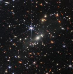 Webbovo první hluboké pole. Kromě mnoha jiných věcí na snímku vidíme též efekty silného gravitačního čočkování.
Zdroj: https://stsci-opo.org/