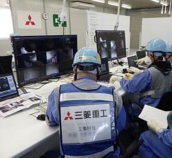 Pracovníci při průzkumu možností proniknutí robotů do kontejnmentu druhého bloku průchodem X-16 (zdroj TEPCO).