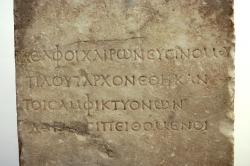 Pěkně čitelný řecký nápis z římské doby, kolem roku 100 n. l., tzv. Plútarchova stéla: „Delfští spolu s Chaironejskými věnovali tuto (Plútarchovu) podobu podle příkazu Amfiktyonie.“ Archeologické muzeum v Delfách, N 4070. Kredit: Zde, Wikimedia Commons. Licence CC 4.0.