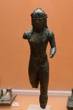Kúros (?) s věncem na dlouhých vlasech. Možná Dionýsos? Drobný bronz, kolem 550 před n. l. Archeologické muzeum v Delfách. Kredit: Zde, Wikimedia Commons. Licence CC 4.0.