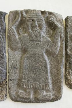 Deska z chrámu paláce v Tell Halaf (SV Sýrie u hranice s Tureckem), 9. století před n. l. Reliéf Kumarbiho nebo boha analogického s Kumarbim, kdysi mnohem dříve byl hlavním bohem Churritů. V rukou drží srp a mužství svého otce. (Viz chetitský epos Vládci nebes 8-41, řecká analogie v Papyru Derveni XIII.4; vzdálenější u Hésioda, Theogonie 159-184.) Pergamonmuseum Berlin (Vorderasiatisches Museum Berlin). Kredit: Zde, Wikimedia Commons. Licence CC 4.0.