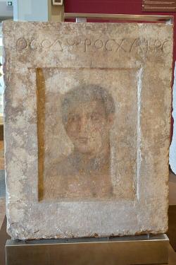 Náhrobní stéla s portrétem mladého muže, malba enkaustikou na mramoru. Théby, 1. století před n. l. Archeologické muzeum v Thébách. Kredit: Zde, Wikimedia Commons. Licence CC 4.0. Náhrobní stéla s portrétem mladého muže, malba enkaustikou na mramoru. Théby, 1. století před n. l. Archeologické muzeum v Thébách. Kredit: Zde, Wikimedia Commons. Licence CC 4.0.