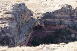 Sedimentární výchozy geologického souvrství Elliot, z nichž nejspíš pocházejí i dinosauří fosilie, náhodně objevované Sany v době před vznikem vědecké paleontologie. Tyto jeskyně v údolí Matalane se nacházejí na území distriktu Leribe v Lesothu. Kredit: Paramente Phamotse; Wikipedia (CC BY-SA 3.0)