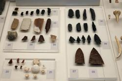 Neolitické nástroje z jeskyně Franchthi a rozpracované ozdoby z mušlí Cerastoderma glaucum. Obsidián (5800 až 3700 před n. l.) a pazourek (5800 až 5300 před n. l.). Archeologické muzeum v Naupliu. Kredit: Zde, Wikimedia Commons. Licence CC 4.0.