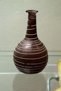 Sklo z římské doby. Láhev, vínové sklo s bílým vláknem spirálovitě ovíjejícím tělo. Východní Středomoří. NM-H10 1813. Kredit: Zde, Wikimedia Commons. Licence CC 4.0.