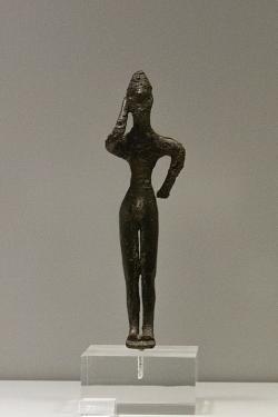 Drobná bronzová figurka vojáka (v pravé ruce měl kopí) z dekorace kulaté rukojeti kotle na trojnožce. 725-700 před n. l. Národní archeologické muzeum v Athénách, č. 7729. Kredit: Zde, Wikimedia Commons. Licence CC 4.0.