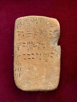 Tabulka s nápisem v lineárním písmu A, z paláce v Petras. Archeologické muzeum v Sitii, S.M. 9099. Může zaznamenávat počet zaměstnanců a množství obilovin (příděly, naturálie). Kredit: Zde, Wikimedia Commons. Licence CC 4.0.