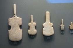 Kykladské idoly tvaru violy z Kimolu, Despotika, Paru a Naxu, 3200-2800 před n. l., kultura Grotta-Pelos. Když se sošce zlomil krk (1), opravila se pomocí drátu, skobičky nebo provázku skrz nově udělané otvory. Národní archeologické muzeum v Athénách, inv. č. 3937, 4874, 4853, 6140.3. Kredit: Zde, Wikimedia Commons .