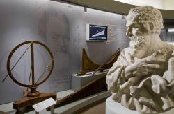Galileo Galilei v podobě sochy, kterou v letech 1674-1677 udělal Carlo Marcellini, shlíží na repliky a modely svých přístrojů vyrobené v 18. a 19. století. Kredit: BernzBernz, Wikimedia Commons. Licence CC 3.0.