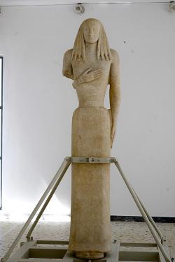 Tzv. Koré z Théry, z 2. poloviny 7. století před n. l. Mramor, výška 248 cm. Nález z pohřebiště Staré Théry, import z naxijské dílny. Archeologické muzeum na Théře, zvláštní výstava ze záchranného výkopu, adjustace je provizorní. Kredit: Zde, Wikimedia Commons. Licence CC 4.0.