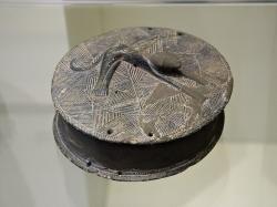 Pyxis s reliéfem ležícího psa na víčku. Chlorit nebo steatit, průměr 12,5 cm. Zakros, Údolí mrtvých. EM ΙΙA, 2600 až 2300 před n. l. Archeologické muzeum v Irakliu, Λ2719. Kredit: Zde, Wikimedia Commons. Licence CC 4.0.