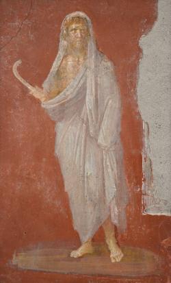 Saturn s hlavou chráněnou zimním pláštěm, v pravé ruce drží kosu, freska z Domu Dioskúrů v Pompejích. Kredit: Archeologické muzeum Neapol, Wikipedia. CC BY-SA 2.0. https://en.wikipedia.org/wiki/Saturn_(mythology)#/media/File:Saturn_with_head_protected_by_winter_cloak,_holding_a_scythe_in_his_right_hand,_fresco_from_the_House_of_the_Dioscuri_at_Pompeii,_Naples_Archaeological_Museum_(23497733210).jpg