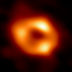 První snímek supermasivní černé díry Sgr A* v centru naší Galaxie. Je výsledkem propojení osmi stávajících radioteleskopů na celé planetě do jednoho virtuálního dalekohledu "velikosti Země"- dalekohledu Event Horizon Telescope (EHT). Snímek zachycuje světlo ohnuté silnou gravitací černé díry, která je čtyř milionkrát hmotnější než naše Slunce. Snímek černé díry Sgr A* je průměrem různých snímků, které EHT Collaboration získala ze svých pozorování v roce 2017.  Kredit: EHT Collaboration, CC 4.0   https://en.wikipedia.org/wiki/Event_Horizon_Telescope