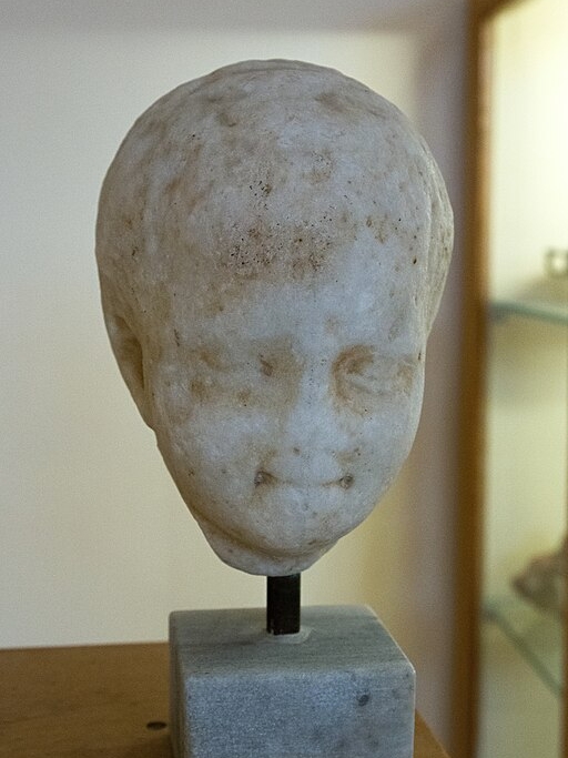 Hlava dítěte nalezená na ostrově Keós. Helénistická nebo římská doba. Archeologické muzeum na Syru. Kredit: Zde, Wikimedia Commons. Licence CC 4.0.