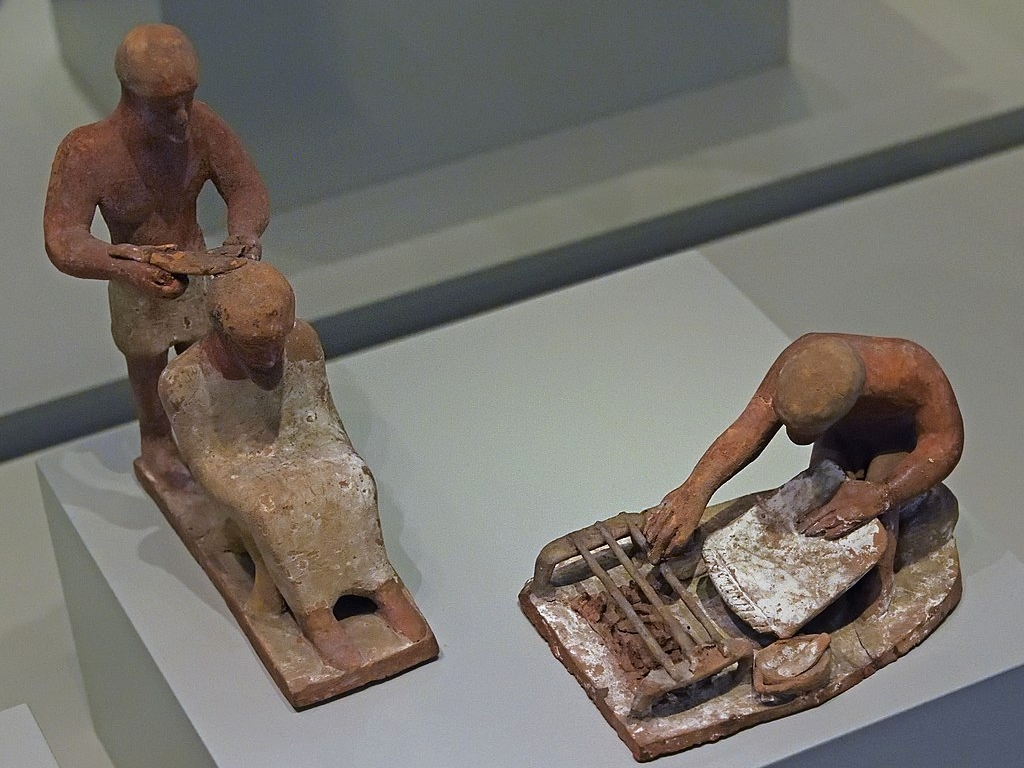 Kadeřník při práci a muž u grilu. Drobné terakoty, 5. století před n. l. Altes Museum Berlin. Kredit: Dosseman, Wikimedia Commons. Licence CC 4.0.