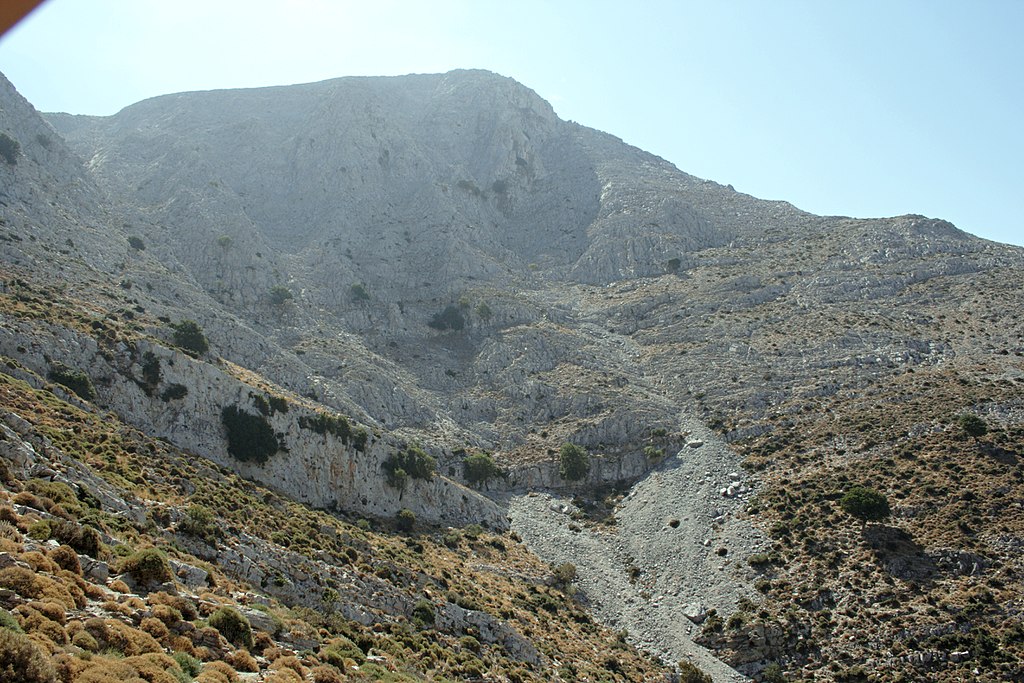 Z pěšinky nad jeskyní vypadá hora pořád dost nepřístupně. Kredit: Zde, Wikimedia Commons. Licence CC 4.0.