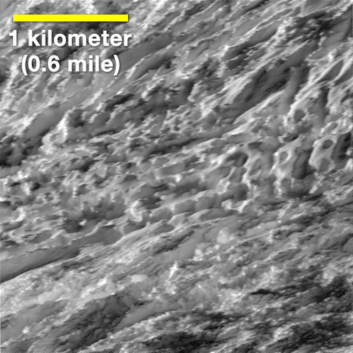 Snímek povrchu Enceladu pořízený z výšky jednoho kilometru. Z  prasklin ledového příkrovu by mohly tryskat zrna ledu obsahují velké a komplexní molekuly organických látek. Mělo by jít o produkty chemických reakcí mezi kamenným jádrem tohoto Saturnova
