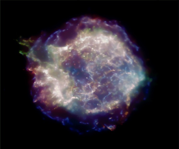 Zbytek po supernově Cas A ve 3 rentgenových barvách (Chandra X-ray Observatory, 19.8.2002). Vztah mezi jasností, barvou a polohou materiálu na obrázku ukazuje, kde se nacházel materiál hvězdy před explozí. Jasné „uzlíky“ vlevo obsahují jen nepatrné množství železa, červené filamenty jsou na železo bohaté. Modrá oblast vpravo je viditelná přes absorbující prach, proto se jeví chudá na rentgenové paprsky. 